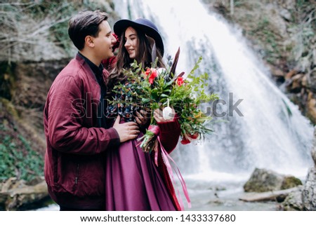 A loving, stylish, young couple in love on the background of a waterfall.