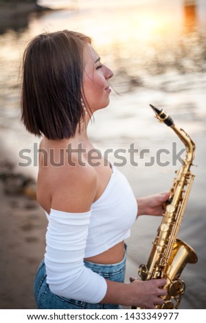Woman playing the saxophone at sunset
