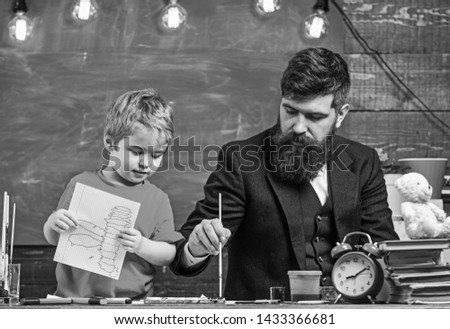 Daddy showing son how to use watercolors. Cute kid holding a drawing in his hands. Creativity concept.