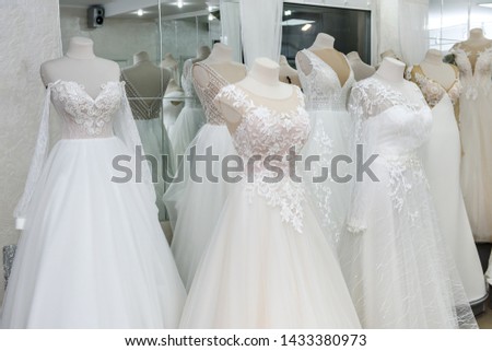 Fashion wedding dresses on hanger and mannequins in salon