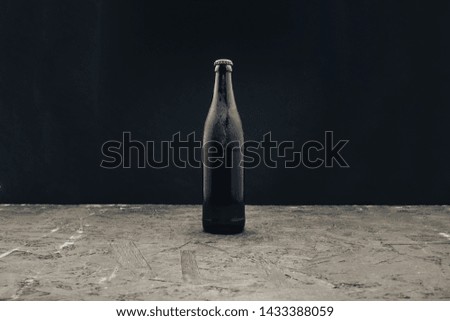 Glass brown Bottle of beer on a dark wooden table and black background behaid.