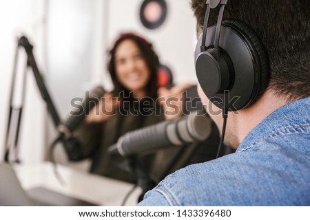 Man and woman in white shirts podcasters interview each other for radio podcast Royalty-Free Stock Photo #1433396480