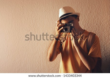 Man with a hat taking a picture with his camera.
