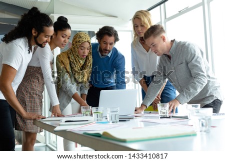 Front view of diverse business people working together on laptop at conference room in a modern office Royalty-Free Stock Photo #1433410817