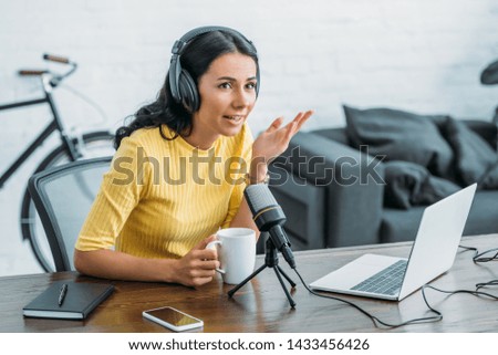 attractive radio host speaking in microphone while holding coffee cup