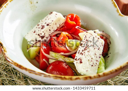 Vintage Stylized Fresh Vegetable Salad with Fragrant Herb Cheese on Rustic Hay Background. Macro Photo of Large Sliced Tomatoes, Cucumbers, Red Bell Pepper, Ricotta and Onion in Old Ceramic Bowl
