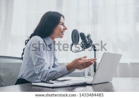 smiling radio host gesturing while recording podcast in radio studio