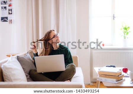 A young female student sitting on sofa, using laptop when studying. Royalty-Free Stock Photo #1433493254