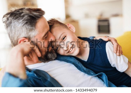 Mature father with small son sitting on sofa indoors, resting. Royalty-Free Stock Photo #1433494079