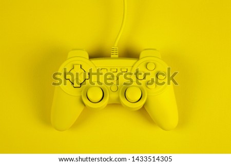 a yellow painted video game controller on a plain background of the same color. Minimal color still life photography