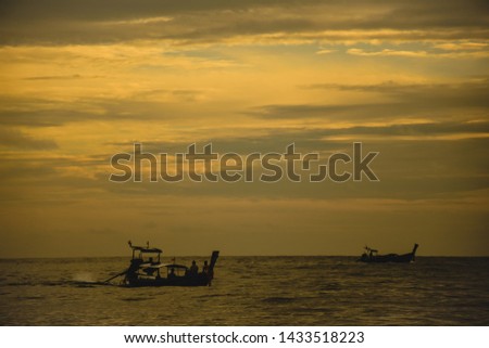 Silhouette of tourists enjoy the beautiful golden sunset with the traditional  boat in a horizon sailing by locals. Boat trips on Koh Phi Phi Island. Famous destination in Southeast asia. 