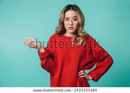 Image of confused young woman posing isolated over blue wall background.