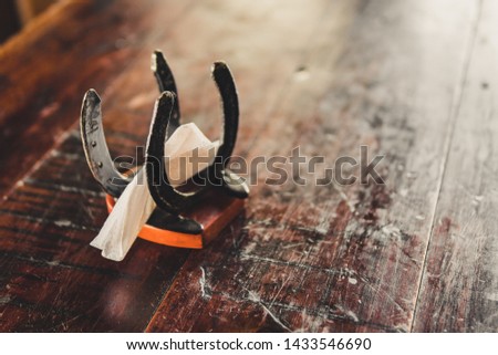 Napkin holder made of horseshoes. It's on a wooden table. 