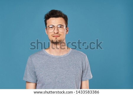 The guy in the gray T-shirt and glasses blue background cropped look