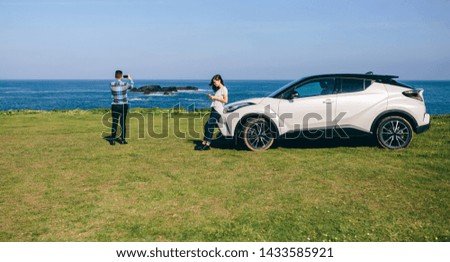 Young couple traveling by car making a stop to photograph the landscape