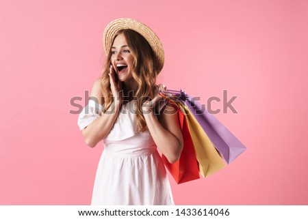 Image of beautiful amazed woman wearing straw hat wondering and holding shopping bags isolated over pink background