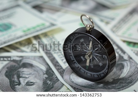 Closeup of a compass placed on U.S. Dollar banknotes Royalty-Free Stock Photo #143362753