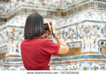 Beautiful woman tourist Held camera to capture the memories. Wat Arun Temple in Thailand. using as background  travel concept with copy spaces for your 