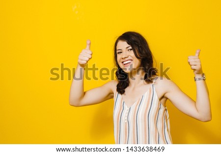 Image of excited young asian woman standing isolated over yellow background make winner gesture.