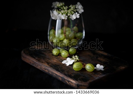 Gooseberry and flowers in glass cup on a wooden Board, still life with berries in rustic style