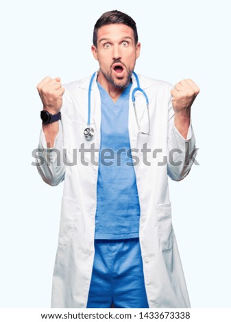 Handsome doctor man wearing medical uniform over isolated background celebrating surprised and amazed for success with arms raised and open eyes. Winner concept.