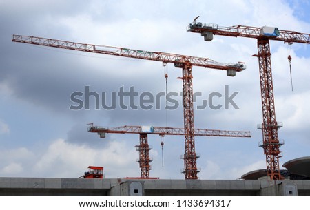 Tower crane on top of building, used in construction site background with beautiful sky