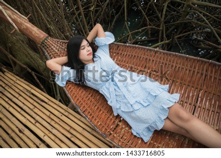 A cute woman in a blue dress is sitting on a crib in a mangrove forest.
Relax on a holiday at the mangrove forest.