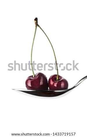 Two red sweet berries in a tablespoon in a white background in vertical format