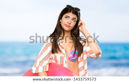 Teenager girl on summer vacation having doubts and with confuse face expression at the beach