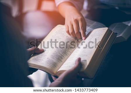 Male adults are reading the Holy bible by pointing to the character and to share the gospel to youth. The cross symbol, The books of the Bible, Concepts of Christianity. Royalty-Free Stock Photo #1433773409