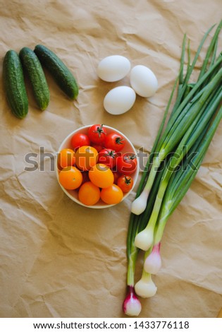 cucumbers, cherry tomatoes, eggs, green onions are on craft paper