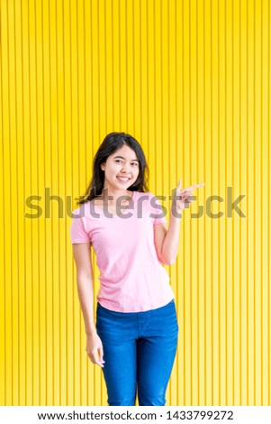 young asian woman happiness standing on yellow wall for copy sapce