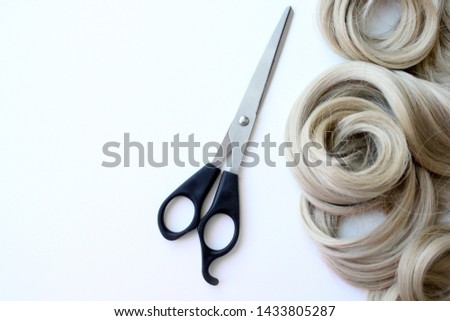 Composition with blond hair, scissors and space for text on a colored background. Hairdressing services. For business card or poster.