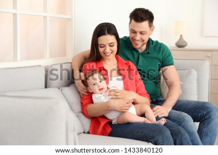 Happy couple with adorable baby on sofa at home. Family time