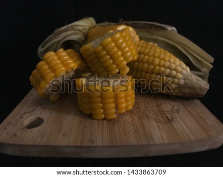 Various photographed angles of Jagung Rebus or steamed corn on the cob; very popular traditional snack. Set on the wooden plate with a black background. Images.