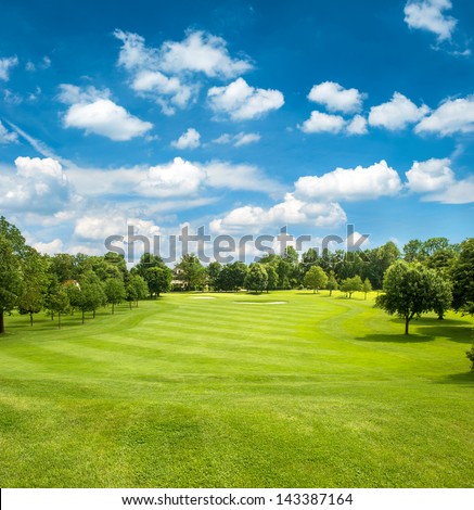 green golf field and blue cloudy sky. european landscape Royalty-Free Stock Photo #143387164