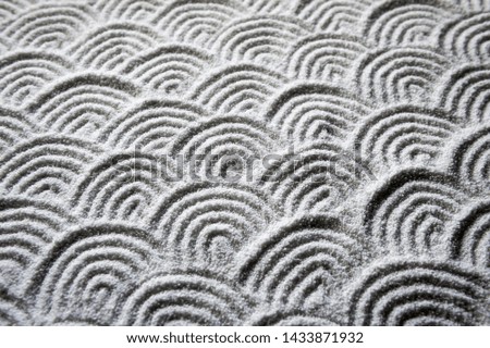 Graphic wave patterns raked into the white sand of a Japanese Zen garden for a full frame background of tranquility