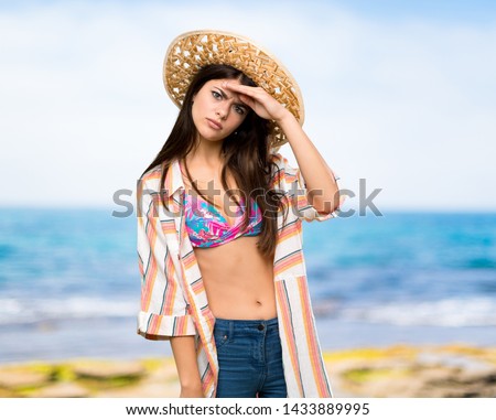 Teenager girl on summer vacation looking far away with hand to look something at the beach