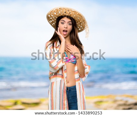 Teenager girl on summer vacation surprised and shocked while looking right at the beach