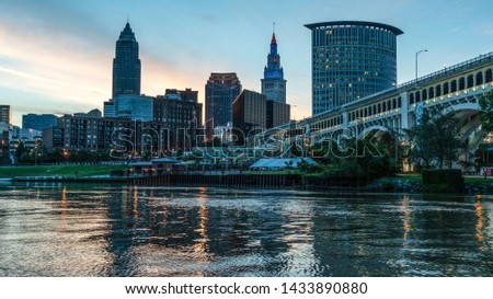 Small City Urban Skyline Lights Of Cleveland Ohio Along The Cuyahoga River With Major Bridge In Background.