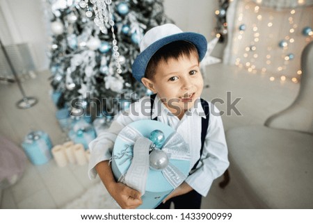 Portrait of a cute little boy in a hat, holding a gift box in his hands. Christmas atmosphere