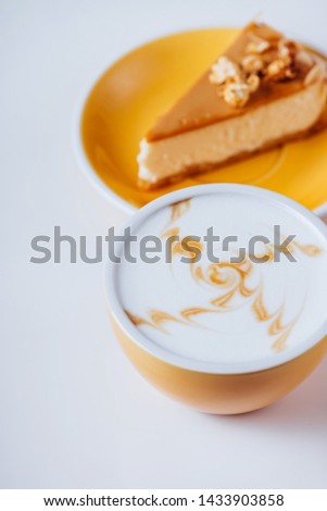 Cup of hot cappuccino coffee with cake on white table with copy space