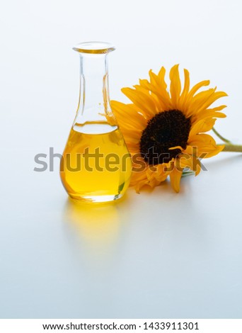 Sunflower oil in a carafe with a sunflower blossom next to it. Isolated on white