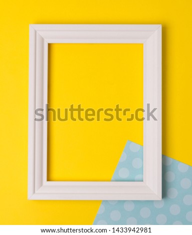 Empty frame flat lay on yellow and blue polka dot background with copy space. Minimal concept