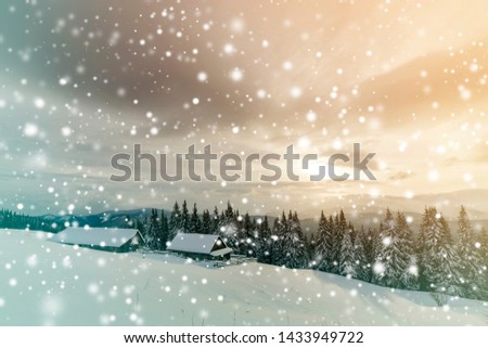 Winter mountain landscape. Old wooden houses on snowy clearing on background of mountain ridge, spruce forest and cloudy sky. Happy New Year and Merry Christmas card.