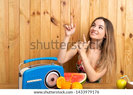 Young woman in swimsuit with lots of fruits pointing with the index finger a great idea