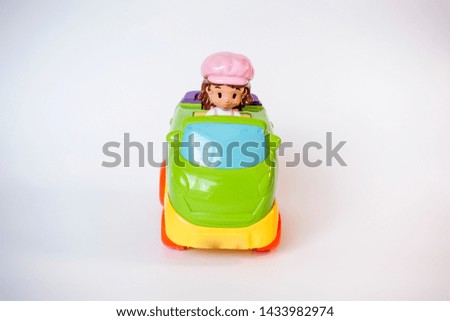 A wonderful toy car composition that stands on a white background with his dog sitting behind a green toy car driver.