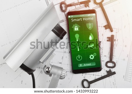 Home security concept - smartphone with smart home app and surveillance cctv camera on the desk