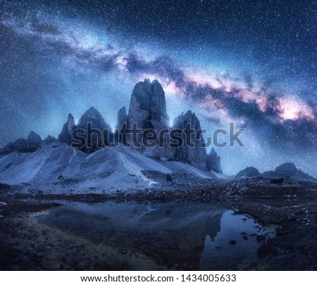 Milky Way over mountains at night in summer. Colorful landscape with alpine mountains, lake, blue sky with milky way and stars, reflection in water, high rocks. Dolomites, Italy. Space and galaxy