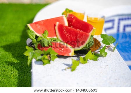 Summer holiday tropical concept. Fresh orange juice and watermelon juice and pineapple on border of a swimming pool.